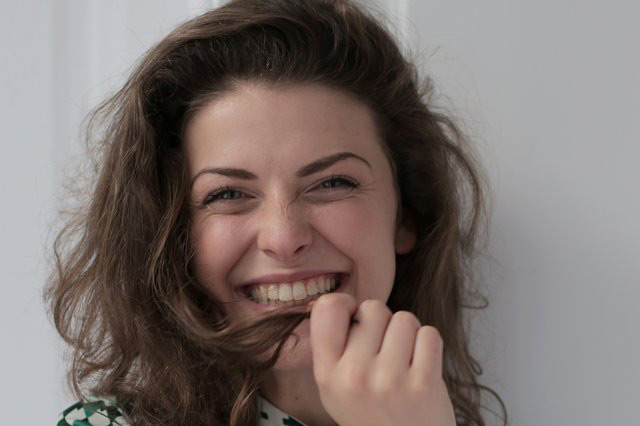 Una donna sorride con un po’ di imbarazzo dopo aver ricevuto un complimento inaspettato dall’ex.