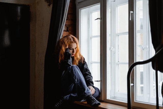 Una donna guarda pensierosa fuori dalla finestra perché sente la mancanza dell'ex.
