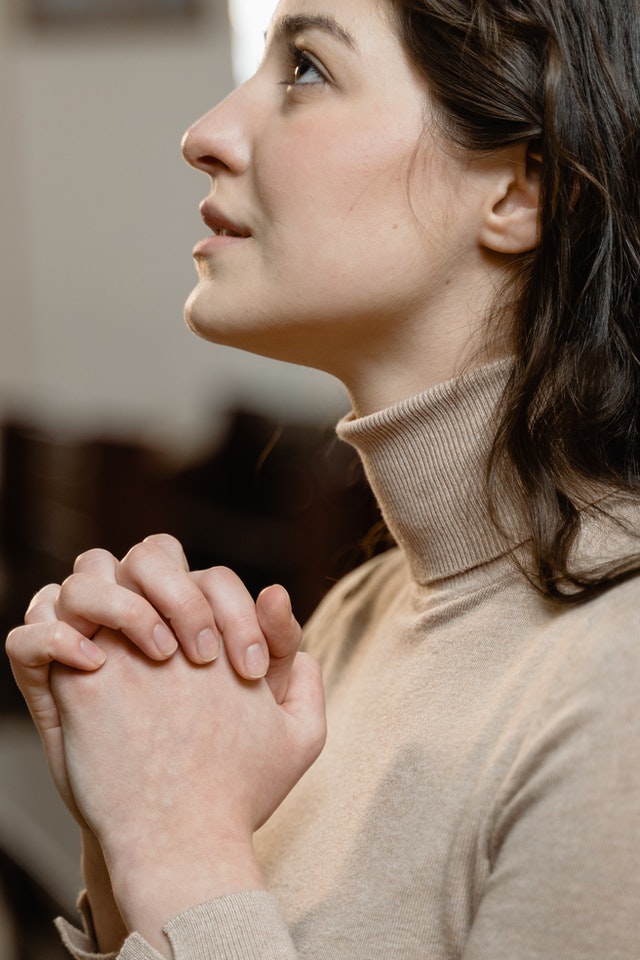 Una donna con le mani giunte supplica il marito di non lasciarla.