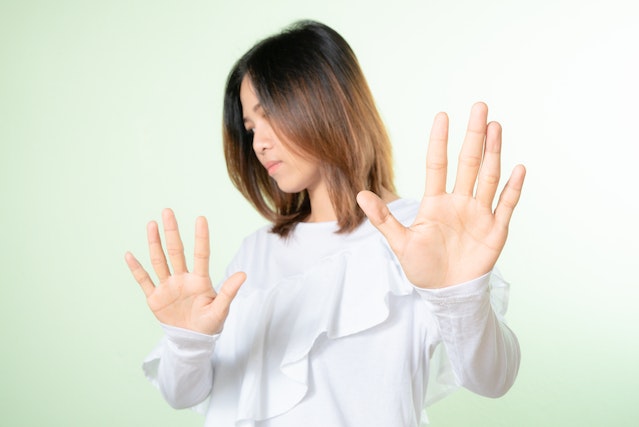 Una giovane donna fa un gesto di rifiuto con le mani, simbolo della necessità di stabilire dei limiti e difendere la propria dignità.