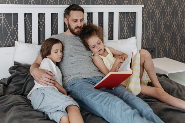 Un uomo legge una storia ai suoi due figli prima di dormire, mostrando di essere un padre presente e responsabile dopo il divorzio.