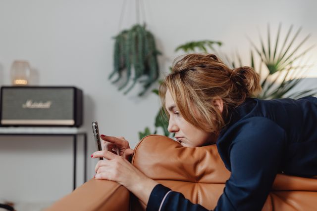 Una donna guarda il telefono delusa perché l’ex ignora i suoi messaggi.