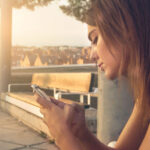 Una donna guarda il telefono delusa perché l’ex non risponde ai suoi messaggi o alle sue chiamate.