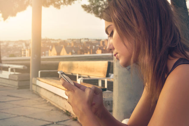 Una donna guarda il telefono delusa perché l’ex non risponde ai suoi messaggi o alle sue chiamate.